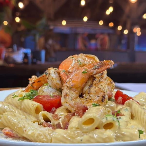Grilled shrimp and scallops atop creamy pasta with bacon bits and cherry tomatoes.